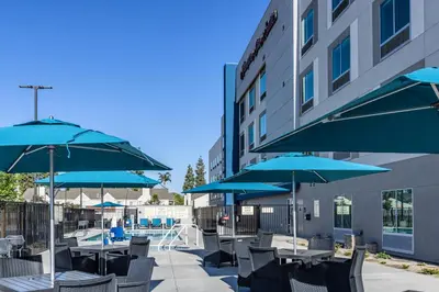 a patio with tables and chairs with blue umbrellas at Hampton Inn & Suites Bakersfield Central in Bakersfield