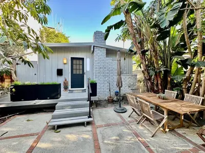 a patio with a wooden table and chairs and a house at Charming Zen Venice Beach 3BR Home w/Patio & W/D in Los Angeles