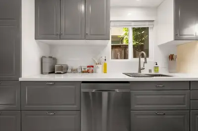a kitchen with gray cabinets and a stainless steel dishwasher at Charming Zen Venice Beach 3BR Home w/Patio & W/D in Los Angeles