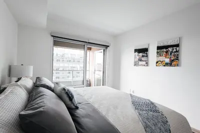a white bedroom with a large bed and a window at Luxurious Hollywood condo in Los Angeles