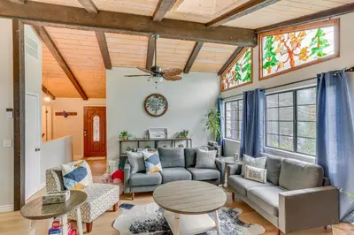 a living room with a couch and a table at Crestline Home with Private Hot Tub Steps to Lake! in Crestline