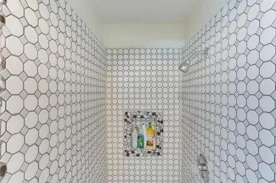 a bathroom with white tiled walls and a shower at Crestline Home with Private Hot Tub Steps to Lake! in Crestline
