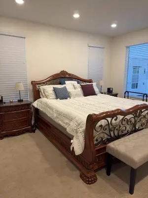 a bedroom with a large wooden bed with pillows at 3 Bedroom Townhome with Large Living Area in Downey