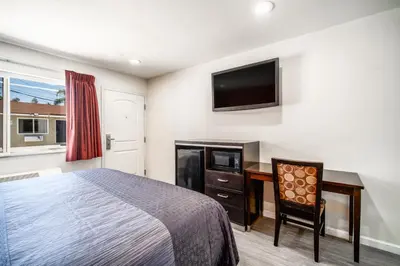 a bedroom with a bed and a desk and a tv at Bell Manor Motel in Bell