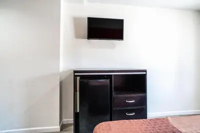 a black refrigerator in a room with a tv on a wall at Bell Manor Motel in Bell