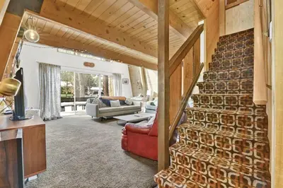 a living room with a brick wall and a staircase at Quail's Call Big Bear~ Walk to Lake & Ski Resort in Big Bear Lake