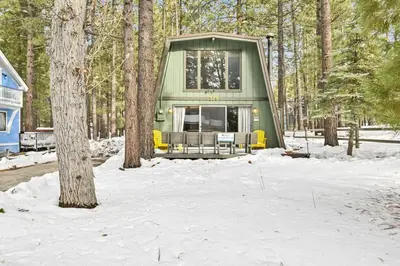 a green cabin in the woods in the snow at Quail's Call Big Bear~ Walk to Lake & Ski Resort in Big Bear Lake