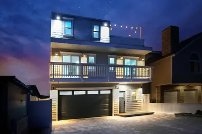 a large house with a garage at night at Steps 2 Beach- Luxury Home, Game Room, Roof Deck, Firepit, Pets OK in Oxnard