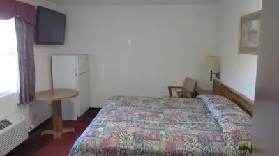 a bedroom with a bed and a table and a refrigerator at Eagle Rock Motel in Los Angeles