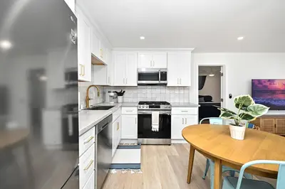 a kitchen with white cabinets and a wooden table at Sunset Beach Retreat next to Water Tower and Ocean in Sunset Beach
