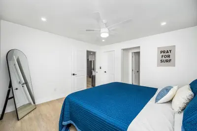a white bedroom with a bed with a blue blanket at 130 Anderson St A in Sunset Beach