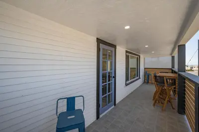 a patio with a table and chairs on a porch at Brand New Home by the Beach & Historic Sunset Water Tower in Sunset Beach