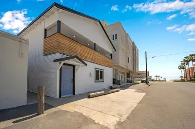 a large white building with a garage on a street at Brand New Home by the Beach & Historic Sunset Water Tower in Sunset Beach
