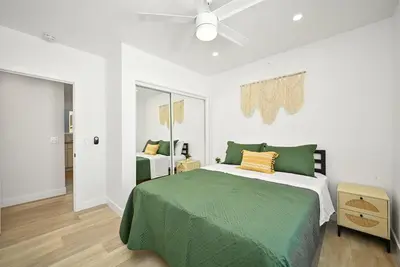a bedroom with a green bed and a ceiling fan at Brand New Home by the Beach & Historic Sunset Water Tower in Sunset Beach