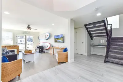 a living room with a couch and a staircase at Sunset Island 3 Level Home on the Water sleeps 10 in Sunset Beach