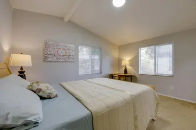 a bedroom with a bed and two windows at Oak View Home - Close to Beaches and Trails! in Oak View
