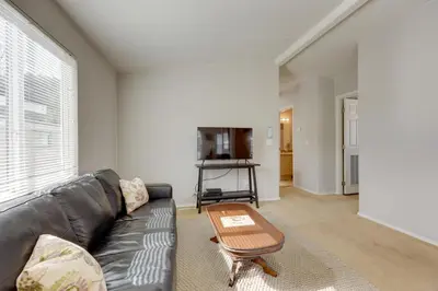 a living room with a black leather couch and a table at Oak View Home - Close to Beaches and Trails! in Oak View