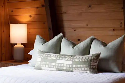 a bedroom with a bed with pillows and a lamp at Pet & Kid Friendly Cozy Cabin, BBQ, Firepit, Outdoor Dining, Forest Views in Lake Arrowhead