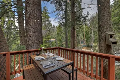 a wooden table on the deck of a cabin at Pet & Kid Friendly Cozy Cabin, BBQ, Firepit, Outdoor Dining, Forest Views in Lake Arrowhead
