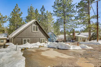 a house is covered in snow in a yard at Cozy Cabin with Deck - 2 Mi to Bear Mountain Resort! in Big Bear Lake