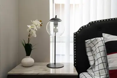 a table with a lamp and a vase with flowers on it at Hollywood 1Bed Apt w Rooftop pool & Panoramic View in Los Angeles