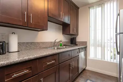 a kitchen with wooden cabinets and a sink at Hollywood 2Bed Apt w Rooftop pool & Panoramic View in Los Angeles