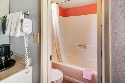 a bathroom with a toilet and a phone on the wall at Hotel Europa Ridgecrest in Ridgecrest