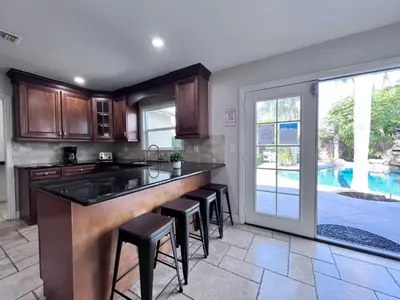 a kitchen with a bar with stools and a pool at Destination #02 in Anaheim