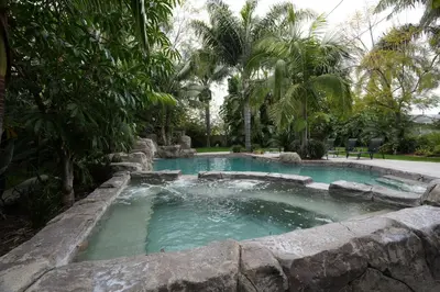 a swimming pool in a garden with a rock wall at Destination #03 in Fullerton