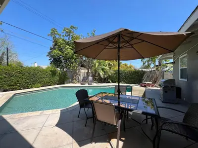 a table with an umbrella next to a swimming pool at Destination #12 in Anaheim