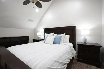 a bedroom with a large bed with white sheets and blue pillows at Nostalgic PoolJacuzzi Home: GameRm1.8 Mi 2Disney in Anaheim