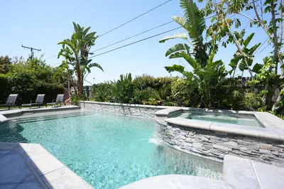 a swimming pool with a stone wall around it at Nostalgic PoolJacuzzi Home: GameRm1.8 Mi 2Disney in Anaheim