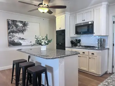 a kitchen with a island with stools and a ceiling fan at Destination #13 in Anaheim