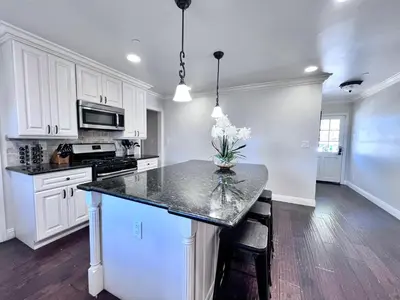 a kitchen with white cabinets and a black counter top at Destination #22 in Anaheim