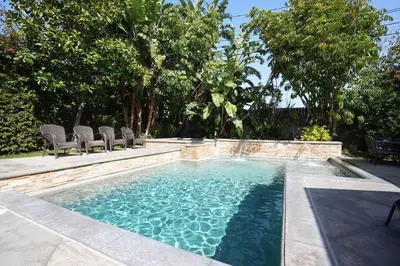 a swimming pool with chairs and trees in a backyard at Classy PoolJac Home: 2 Ensuites 34 Mile2Disney in Anaheim