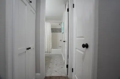 a bathroom with a white door and a hallway with a shower at Destination #39 in Orange