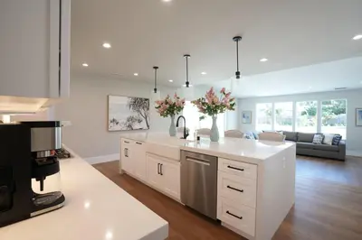 a kitchen with white cabinets and a living room at Destination #45 in Orange