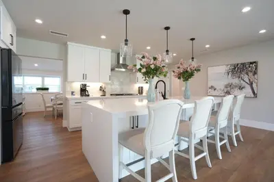 a kitchen with white cabinets and a kitchen island with white chairs at Destination #45 in Orange