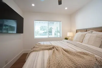 a white bedroom with a large bed and a window at Destination #45 in Orange