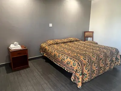 a bedroom with a bed and a table with a phone at Pomona Inn in Pomona
