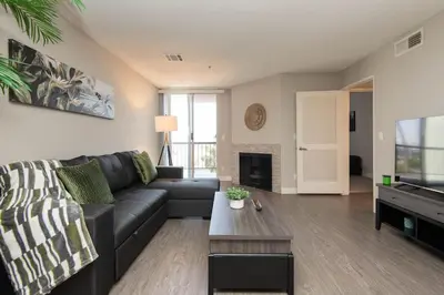 a living room with a black couch and a tv at Hollywood 1Bed Apt w Rooftop pool & Panoramic View in Los Angeles