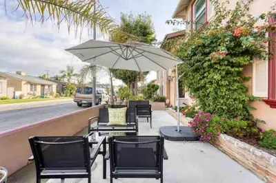 a table and chairs with an umbrella on a sidewalk at Belmont Shore Beach Bungalow, 2 min walk to town! in Long Beach
