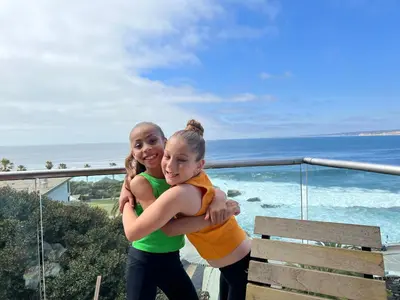 two girls hugging each other on a balcony with the ocean at Luxury 2 Bedroom Suite Apartment in Koreatown in Los Angeles