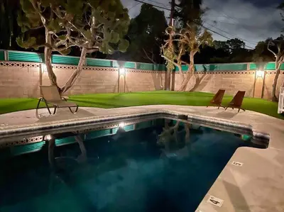a swimming pool with two chairs next to a wall at New cheerful villa, Pool, Spa, Mini Golf, Game room, Fire pit next to Disneyland in Anaheim
