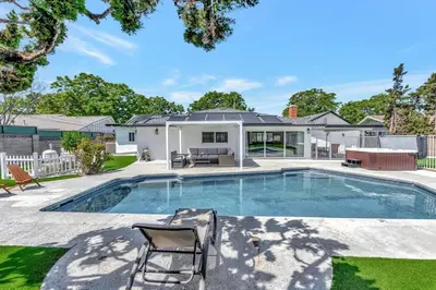 a swimming pool with two chairs and a house at New cheerful villa, Pool, Spa, Mini Golf, Game room, Fire pit next to Disneyland in Anaheim