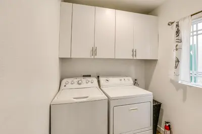 a kitchen with white cabinets and a washer and dryer at 7 Mi to Dtwn! Modern Retreat in East Los Angeles in East Los Angeles