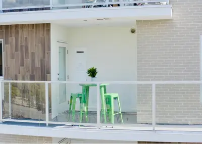 a balcony with two green chairs and a table at Century City Chic 4 sleep free parking 402 in Los Angeles