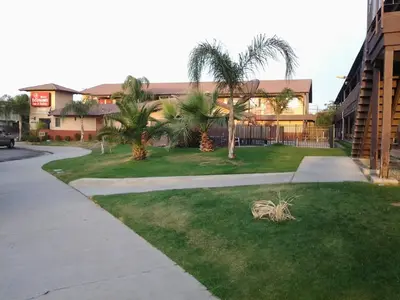 a yard with palm trees in front of a building at Best Economy Inn & Suites in Bakersfield