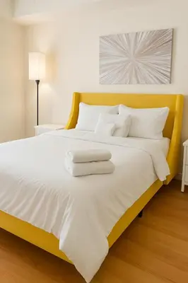 a yellow bed with white sheets and pillows on it at Adorable and Bright 2BD 2BR 740 in Los Angeles