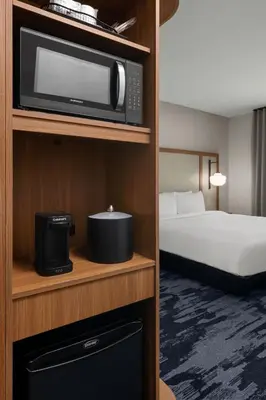 a hotel room with a bed and a microwave at Fairfield by Marriott Inn & Suites Victorville in Victorville